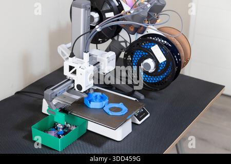 Foto eines 3D-Druckers, der eine blaue Kabelspule aus Kunststoff druckt Stockfoto