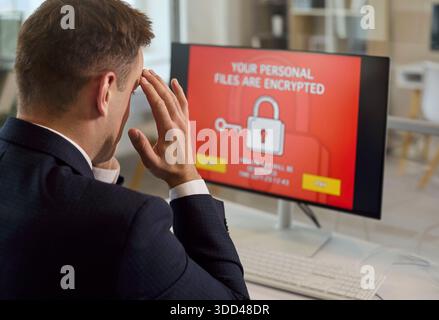Ein gestresster Geschäftsmann reagiert auf Ransomware-Bildschirm mit einer Warnung vor verschlüsselten Dateien Stockfoto