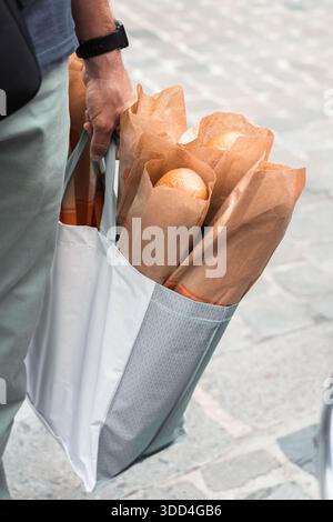 Der Mann hält einen Sack voller Baguettes. Französische Lebensweise, typisches Brot aus der normandie. Essen, frisch gebackenes Brot. Essen einkaufen, Preiserhöhung. Stockfoto