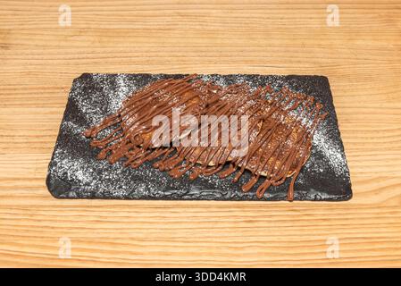 Schokoladenpfannkuchen mit in den Teig eingebetteten Schokoladenchips, garniert mit einer cremigen Schokoladensoße und verziert mit frischen Himbeeren und minzlea Stockfoto