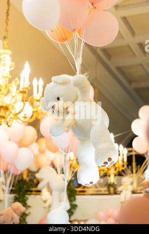 Nahaufnahme eines weißen Plüschteddybären auf Ballons - Dekor für Kinderparty. Stockfoto