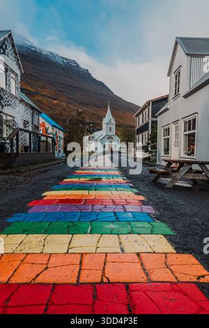 Rainbowstreet, eine der beliebtesten Grafiken in Ost-Island. Blue Church, Geschäfte und Restaurants. Bunte Straße, lgbtq, Frieden, Regenbogen. Stockfoto