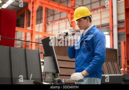 Industriearbeiter, der in einem großen Metallrohr in einer Fabrik einen Schutzhelm trägt || Modell veröffentlicht Stockfoto