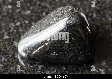 Probe von geschürztem schwarzem Turmalin auf schwarzem Granithintergrund aus Madagaskar aus nächster Nähe Stockfoto