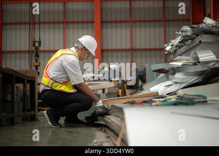Industriearbeiter, der in einem großen Metallrohr in einer Fabrik einen Schutzhelm trägt || Modell veröffentlicht Stockfoto