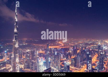 Atemberaubender nächtlicher Luftanblick auf den Burj Khalifa und die Skyline von Downtown Dubai mit beleuchteten Wolkenkratzern und pulsierenden Lichtern der Stadt in den VAE. Stockfoto