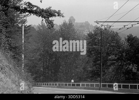 60Er Jahre, 26.08.1967, Deutschland, Solingen, Solingen-Burg, Landkreis Burg an der Wupper, Bergisches Land, Rheinland, Nordrhein-Westfalen, NRW, Burg, unberührter Sitz der Grafen und Herzöge von Berg, Bergburg, Stadtbild, Blick von der Unterstadt über eine Verkehrsstraße auf die Burg in der Oberstadt Stockfoto