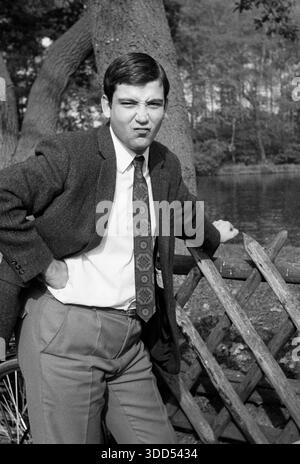 60er Jahre, 05.10.1969, Menschen, Männer, Mann 20 bis 25 Jahre, Foto-Shooting draußen, mittlere Nahaufnahme, kurze Haare, Kurt gekleidet in Jacke mit Krawatte und langer Hose hat Spaß und dreht den Mund hoch, er steht am See des Freizeitparks Grafenmühle in Bottrop, Kirchhellen, Grafenwald, Ruhrgebiet, Westfalen, Nordrhein-Westfalen, NRW, Deutschland Stockfoto