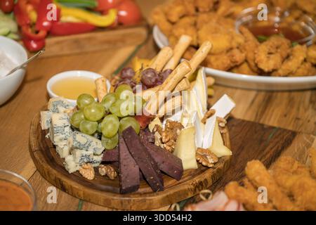 Antipasti-Platte oder Aufschnitt-Platte mit verschiedenen kalten und frittierten Vorspeisen. Wurstwaren und Käse: Aufschnitt, verschiedene Blauschimmelkäse Stockfoto