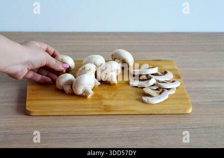 Frische Champignonpilze auf einem hölzernen Schneidebrett. Kochprozess Stockfoto