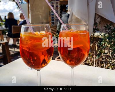 Zwei Gläser Aperol Spritz (aperol, Prosecco, Limonade, Eis, Orangenscheibe) auf einem Tisch vor einem Restaurant in Malta. Stockfoto