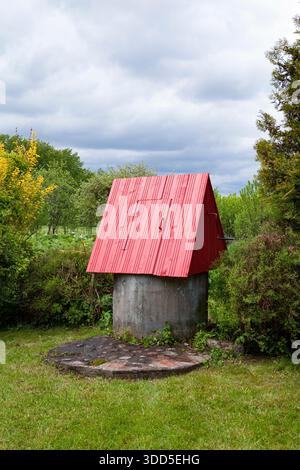 Ein traditioneller ländlicher Brunnen Litauens, der Wasser aus unterirdischen Quellen zieht. Betonringe sind in die Erde versenkt, wo eine Feder den Brunnen füllt Stockfoto