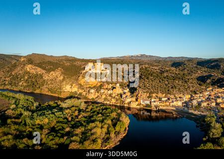 Ein weitläufiges Luftbild fängt ein Dorf am Fluss ein, das in zerklüfteten Hügeln versteckt ist, Miravet, Tarragona, Spanien Stockfoto