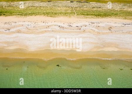 Blick von oben auf die Plage du Mentor in Quiberon mit mehrschichtigen Texturen aus grünem Wasser, hellem Sand und grasbewachsenen Dünen in einer ruhigen, natürlichen Umgebung. Die Komposition ist ruhig und übersichtlich, betont Farbe und Muster. Stockfoto