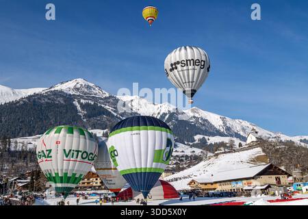 Chateau d'oex, Schweiz - 29. Januar. 2023: Bunte Heißluftballons fliegen und schweben über die Schweizer Alpen beim 43. Internationalen Heißluftballon Stockfoto