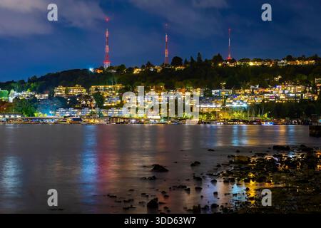 Ein malerisches Panorama fängt die herrliche Skyline der Stadt Seattle ein, die bei Nacht brillant beleuchtet ist und Wolkenkratzer über die ruhige W reflektieren Stockfoto