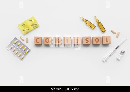 Wort CORTISOL mit Pillen, Ampullen und Spritze auf grauem Hintergrund. Medizinisches Konzept Stockfoto