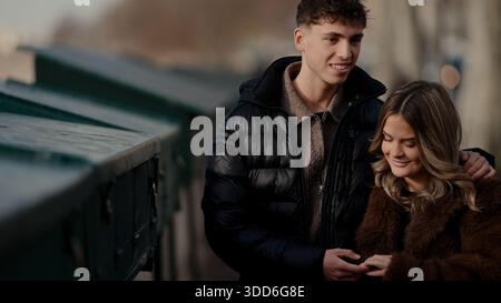 Ein romantisches Paar umarmt sich auf einer Brücke in Paris Frankreich mit der seine im Hintergrund. Der junge Mann und die Frau genießen den Blick auf die Stadt Stockfoto