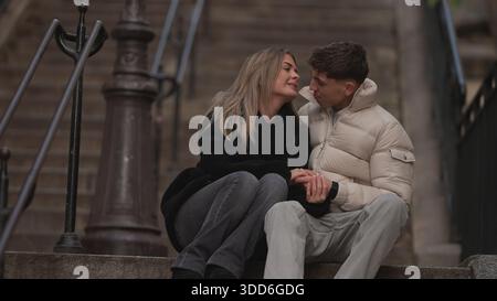 Ein romantisches Paar sitzt auf Steintreppen in Paris, Frankreich, hält Hände und sieht sich mit Liebe und Zuneigung an. Dieses Bild ist perfekt für illus Stockfoto