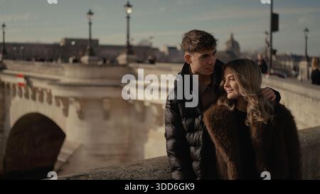 Ein junges Paar umarmt sich auf einer Brücke in Paris Frankreich mit dem Stadtbild im Hintergrund das Bild vermittelt Liebe Reisen und Beziehungen in einem Europäer Stockfoto