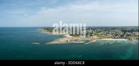 Großer Blick auf den Strand und den Yachthafen von Port aux Moines in Saint-Gildas-de-Rhuys mit klarem türkisfarbenem Wasser, felsiger Küste und einem weitläufigen Küstendorf unter hellem Himmel. Stockfoto