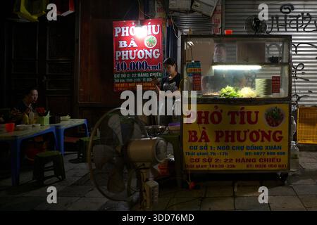 Open-Air-Händlerstand in der Altstadt, wo Pho verkauft wird, ein beliebtes vietnamesisches aromatisches Suppengericht mit Brühe, Reisnudeln und Rindfleisch, mit Sitzplätzen im Freien Stockfoto