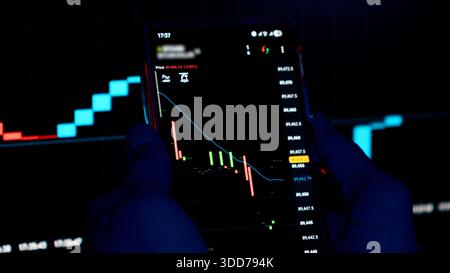 Professioneller Händler, der Börsendiagramme auf einem Smartphone analysiert Stockfoto