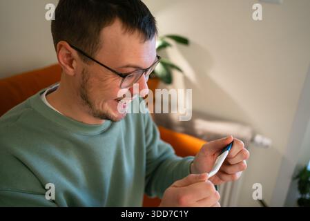 Mann, der begeistert lächelt, während er einen Schwangerschaftstest abhält, mit Freude und Aufregung auf die positiven Ergebnisse reagiert, die Vaterschaft und die Ankunft eines neuen Familienmitglieds antizipiert Stockfoto