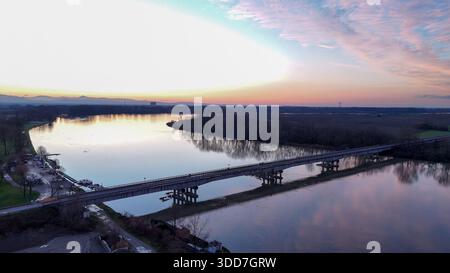 Po River reflektiert leuchtende Farben bei Sonnenuntergang. Luftaufnahme der Brücke, die San Nazzaro verbindet. Monticelli d'Ongina. Emilia Romagna. Italien. Mit Sandextrakt Stockfoto