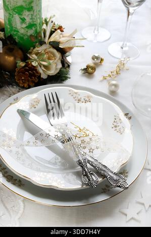 Elegantes und festliches Ambiente, perfekt für den Weihnachtstisch, mit weiß-, Gold- und silbergrauen Farben. Weihnachtsdekoration mit Kugeln, Kerze. Stockfoto