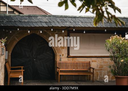 Eine ruhige Gartenszene mit einem rustikalen Holzbogen, Bänken und einer Steinmauer, die ein Gefühl von Ruhe und natürlicher Schönheit weckt. Stockfoto