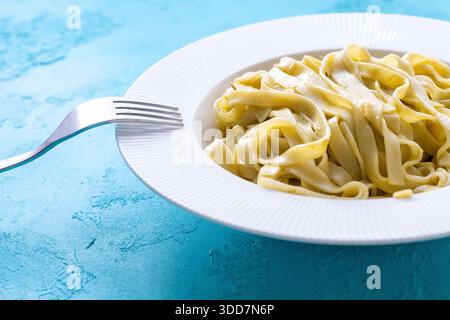 Nahaufnahme von frisch gekochter Tagliatelle-Pasta, umhüllt mit einer reichhaltigen und cremigen Pesto-Sauce. Das leuchtend grüne Basilikum, geriebener Parmesan und seidenweiche Creme Stockfoto