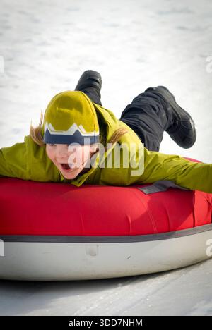 Ein Junge geht Snowtubing am Snow King Mountain in Jackson, Wyoming. Stockfoto