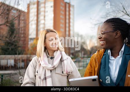 Verschiedene Freundinnen lächelnd und spazierend im Freien Stockfoto
