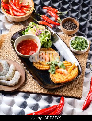Leckeres vietnamesisches Gericht mit Garnelen, Pfannkuchen, Salat und scharfer Paprika auf einem rustikalen Tisch. Stockfoto