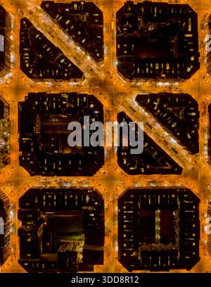 Aus der Vogelperspektive auf die Straßen mit Gittermuster, die in warmem, goldenem Licht beleuchtet sind, im Kontrast zu den dunklen Bausteinen des Viertels Eixample, Barcelona Stockfoto