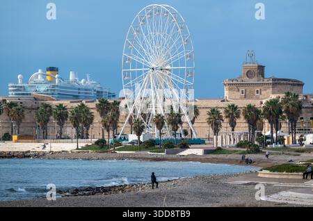 Aus der Vogelperspektive auf das Riesenrad, das sich vor den alten Festungsmauern befindet, mit Palmen, die die Stadtmauern säumen, und einem Kreuzfahrtschiff, das in der ha angedockt ist Stockfoto