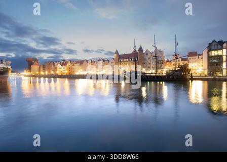 Historische Gebäude entlang des Motlawa-Flusses, die die Lichter der Stadt bei Sonnenuntergang reflektieren, Danzig, Polen Stockfoto