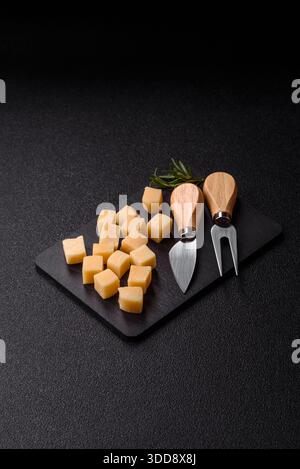 Gewürfelter Cheddar, Gouda oder Parmesankäse auf einem Schneidebrett. Gewürfelter Käse als Lebensmittelhintergrund für Ihr Design Stockfoto