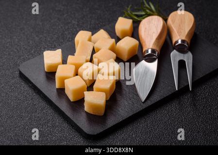 Gewürfelter Cheddar, Gouda oder Parmesankäse auf einem Schneidebrett. Gewürfelter Käse als Lebensmittelhintergrund für Ihr Design Stockfoto