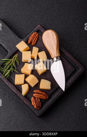 Gewürfelter Cheddar, Gouda oder Parmesankäse auf einem Schneidebrett. Gewürfelter Käse als Lebensmittelhintergrund für Ihr Design Stockfoto