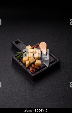 Gewürfelter Cheddar, Gouda oder Parmesankäse auf einem Schneidebrett. Gewürfelter Käse als Lebensmittelhintergrund für Ihr Design Stockfoto