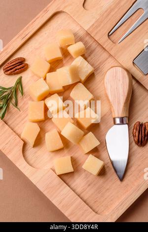 Gewürfelter Cheddar, Gouda oder Parmesankäse auf einem Schneidebrett. Gewürfelter Käse als Lebensmittelhintergrund für Ihr Design Stockfoto