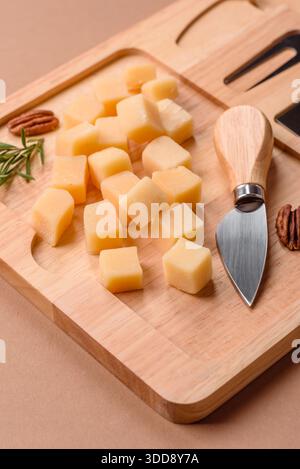 Gewürfelter Cheddar, Gouda oder Parmesankäse auf einem Schneidebrett. Gewürfelter Käse als Lebensmittelhintergrund für Ihr Design Stockfoto