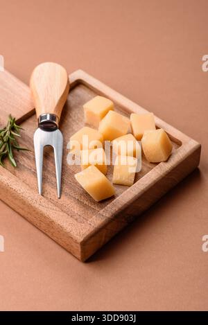 Gewürfelter Cheddar, Gouda oder Parmesankäse auf einem Schneidebrett. Gewürfelter Käse als Lebensmittelhintergrund für Ihr Design Stockfoto