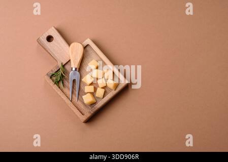 Gewürfelter Cheddar, Gouda oder Parmesankäse auf einem Schneidebrett. Gewürfelter Käse als Lebensmittelhintergrund für Ihr Design Stockfoto