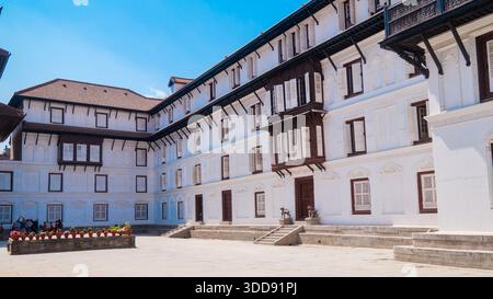 Historisches mehrstöckiges Gebäude mit zahlreichen Fenstern unter einem klaren blauen Himmel im Hanuman Dhoka Palace. Stockfoto