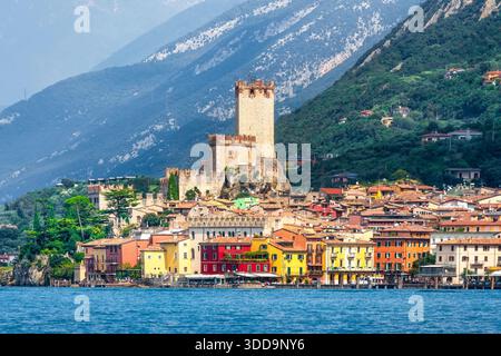 Blick auf die Stadt Malcesine mit ihren farbenfrohen Häusern und dem historischen Scaliger Castle Tower. Wunderschöne Landschaft des Gardasees und der Alpen im Hinterland Stockfoto