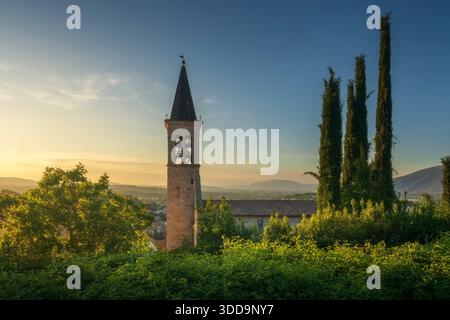 Ein Seitenblick auf den Glockenturm der Kathedrale von Spoleto bei Sonnenuntergang. Die Kathedrale Santa Maria Assunta mit Zypressen und Panoramablick auf Umbrien, Stockfoto