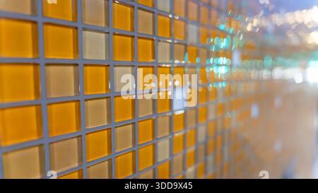 Abstrakte Glasmosaikwand mit warmgelben Fliesen. Stockfoto